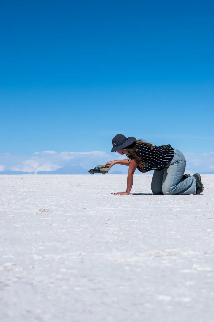 Una pickup overland con la célula vivienda Pioneer de Land Roamer en el Salar de Uyuni empujada por una mujer