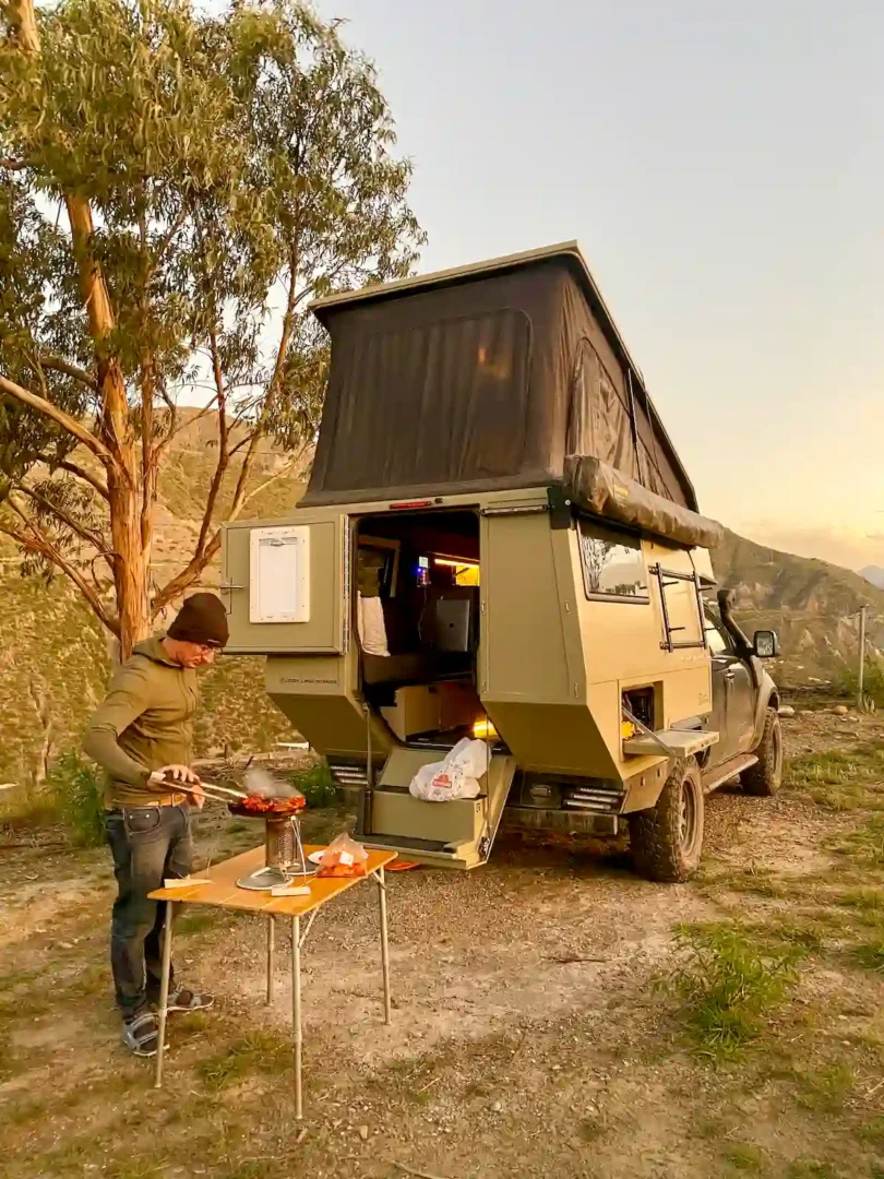 Preparando una barbacoa junto a una pick up overland con la célula vivienda Pioneer de Land Roamer