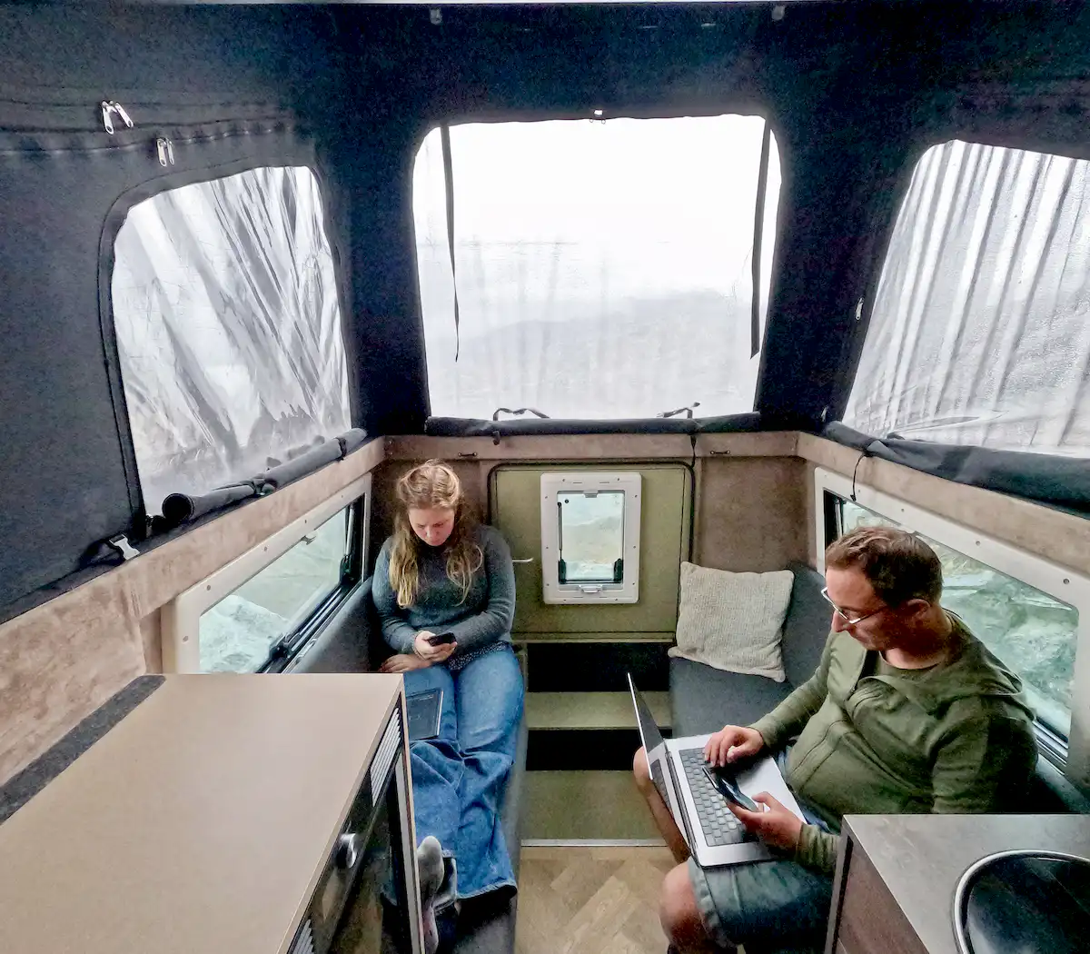 Una pareja teletrabajando en el confortable interior de la célula vivienda Pioneer para pickup overland de Land Roamer