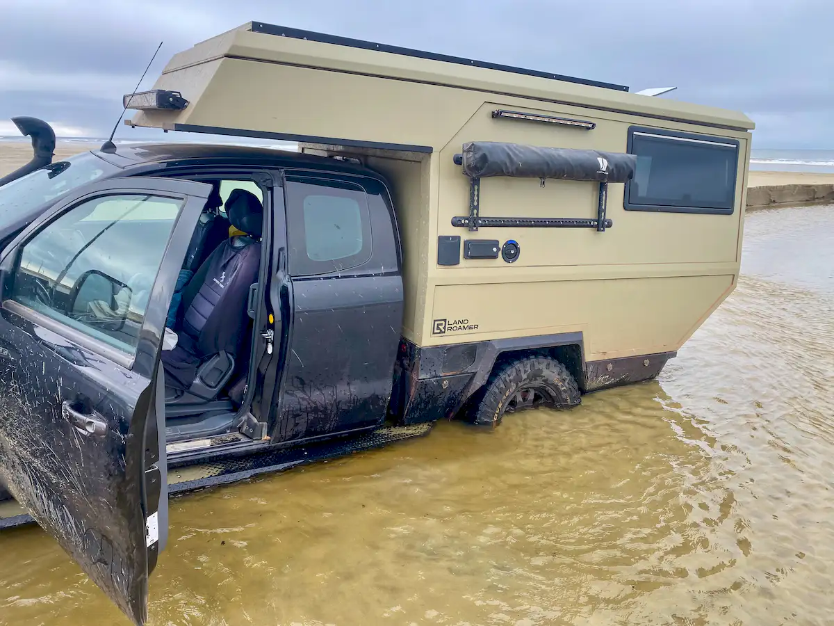 Una pickup overland parada en el agua con la célula vivienda Pioneer de Land Roamer