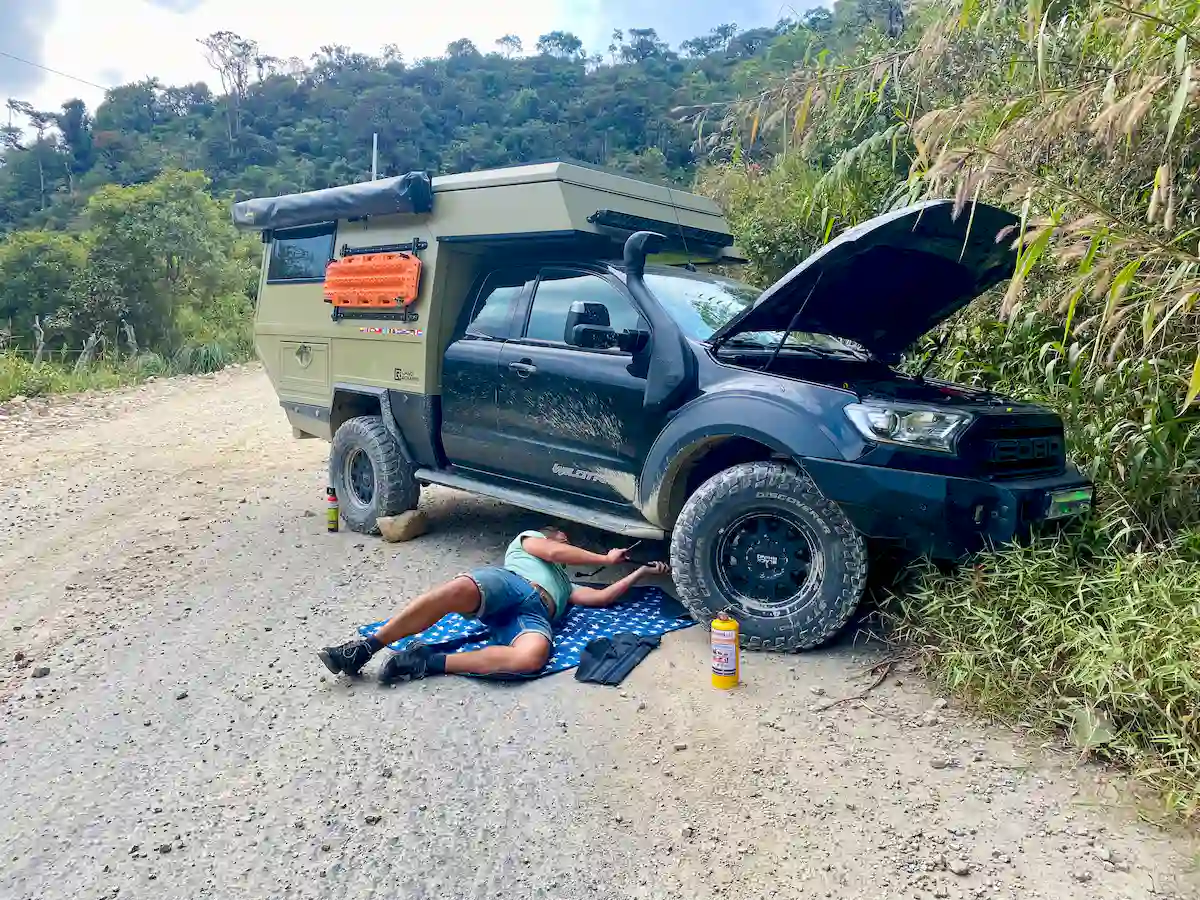 Una pickup overland con la célula vivienda Pioneer de Land Roamer siendo reparada en viaje al borde del camino