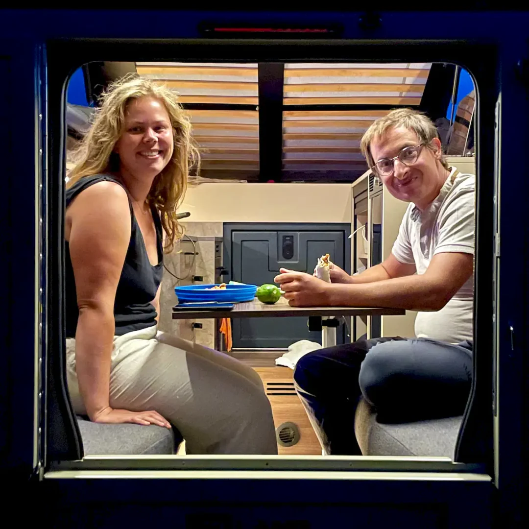 Una pareja cenando cómodamente en el interior de la célula para pickup overland Pioneer de Land Roamer