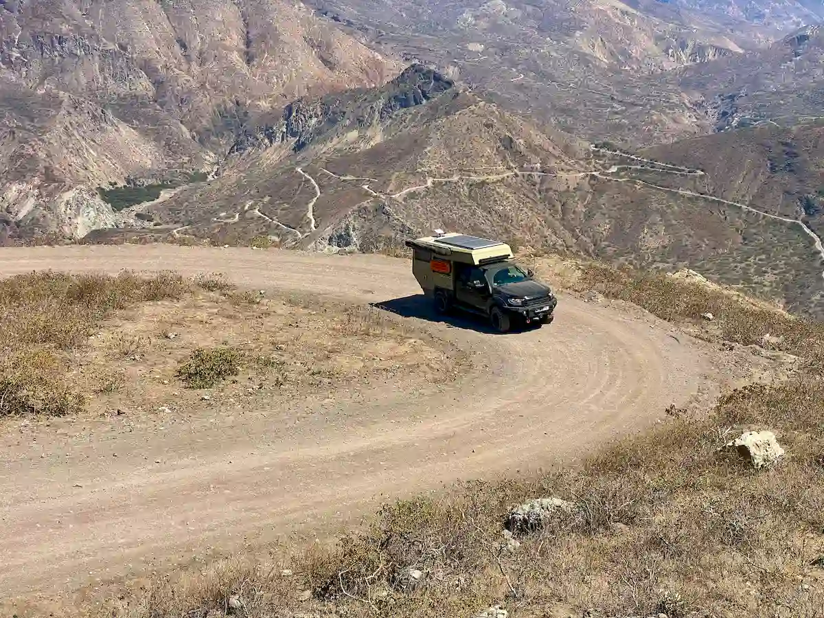 Una pickup overland con la célula vivienda Pioneer de Land Roamer en carretera de montaña offroad