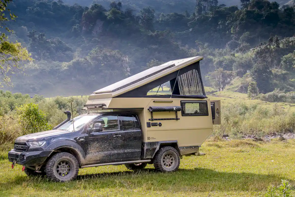 Una pickup overland con la célula vivienda Pionner de Land Roamer acampada en las montañas