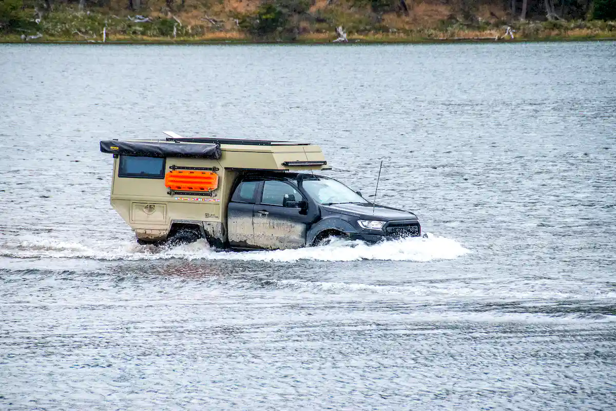 Una pickup overland con la célula vivienda Pioneer de Land Roamer cruzando un río en sudamérica legalmente
