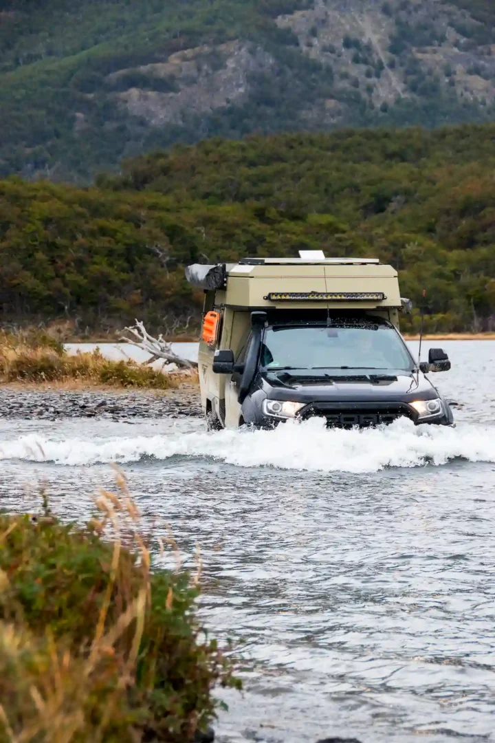 Una pickup overland con célula vivienda Pioner de Land Roamer atravesando un río en sudamérica