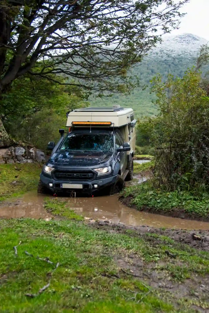 Una pickup con la célula vivienda overland Pioneer de Land Roamer en una pista de barro