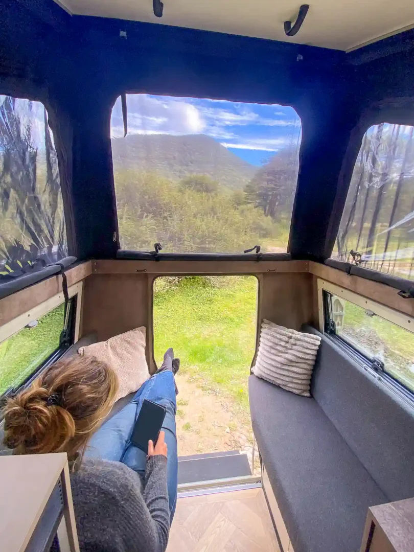 Mujer descansando en el interior confortable de la célula vivienda Pioneer para pick up overland de Land Roamer
